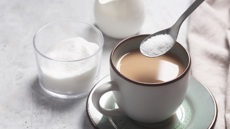 En kvinnas hand som lägger lite stevia till sitt kaffe