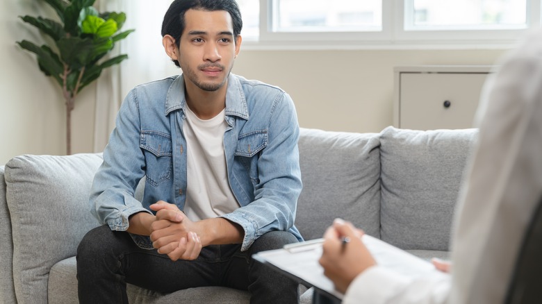 Ung man som pratar med en terapeut eller läkare på kontoret