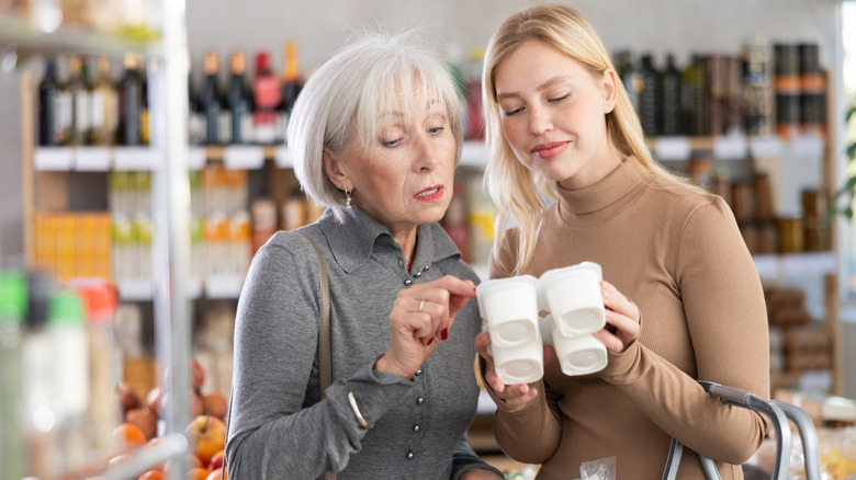 Äldre kvinna och yngre kvinna som tittar på yoghurt