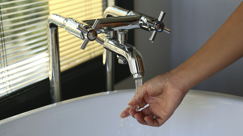 Kvinnans hand med vatten som kommer ut från kran