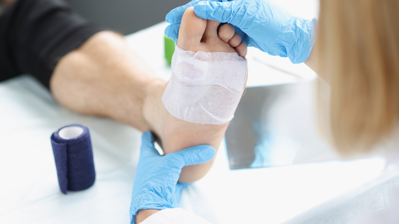Läkare tittar på fotsåret