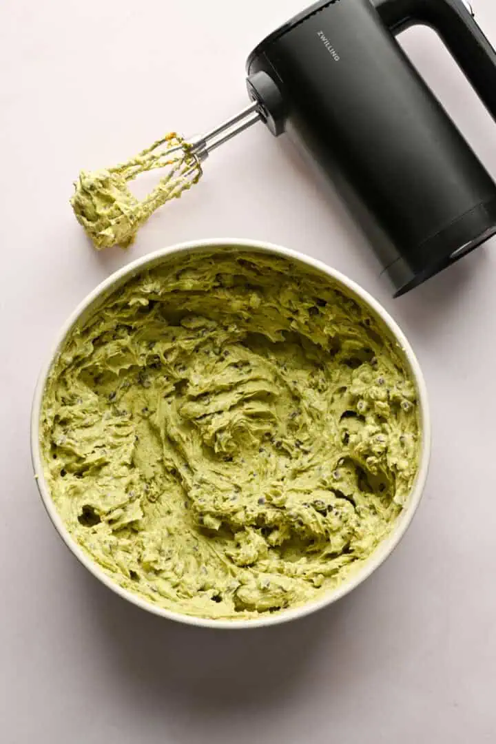 pistagecannoli-fyllningsblandning i en skål med en sladdlös stavmixer bredvid.