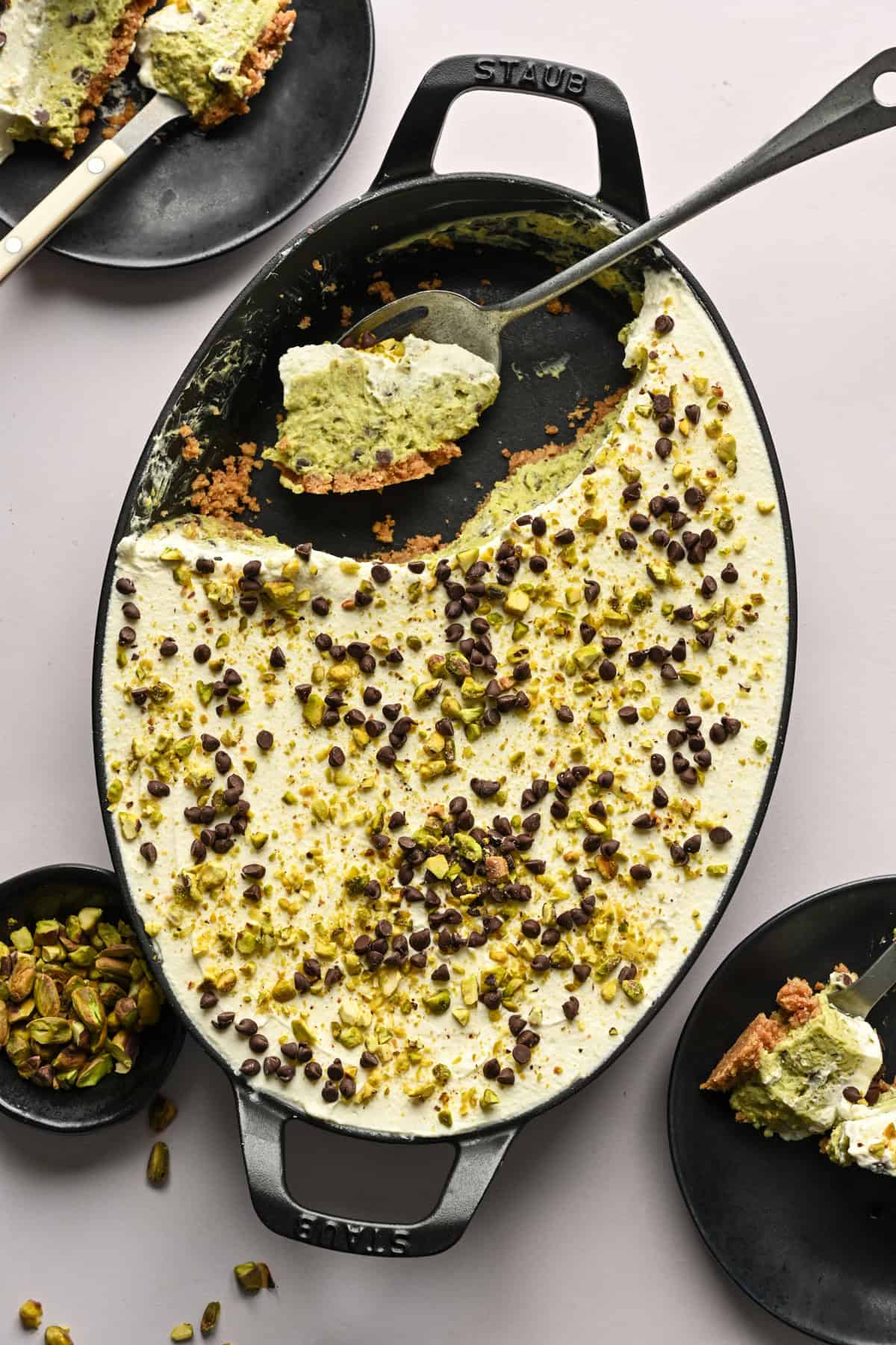 ovanifrån av pistagecannolipaj i en oval gratängform med en bit uttagen och två tallrikar med mer paj.