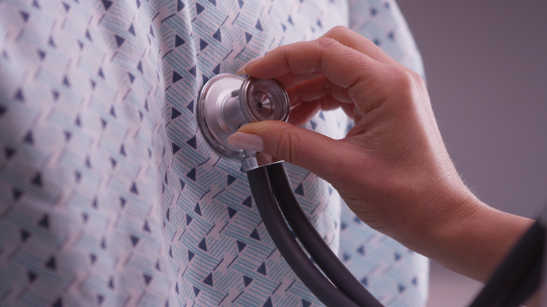 hand som håller steteskopet på patientens bröst