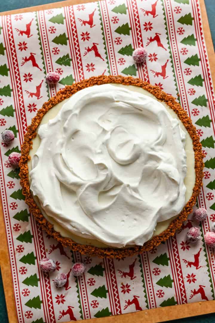 vispad grädde på toppen av tranbärsvit chokladtårta.