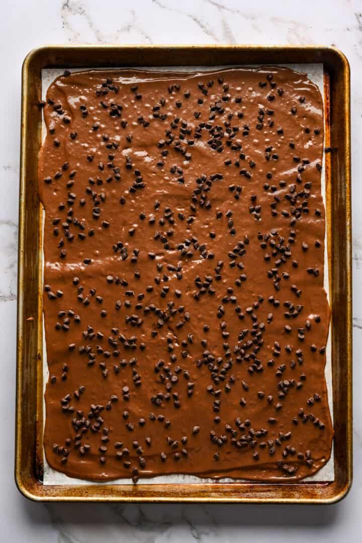 Brownie spröd på en plåt, bred ut över en bit bakplåtspapper.