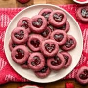Raspberry heart tumavtryck cookies staplade upp på en tallrik.