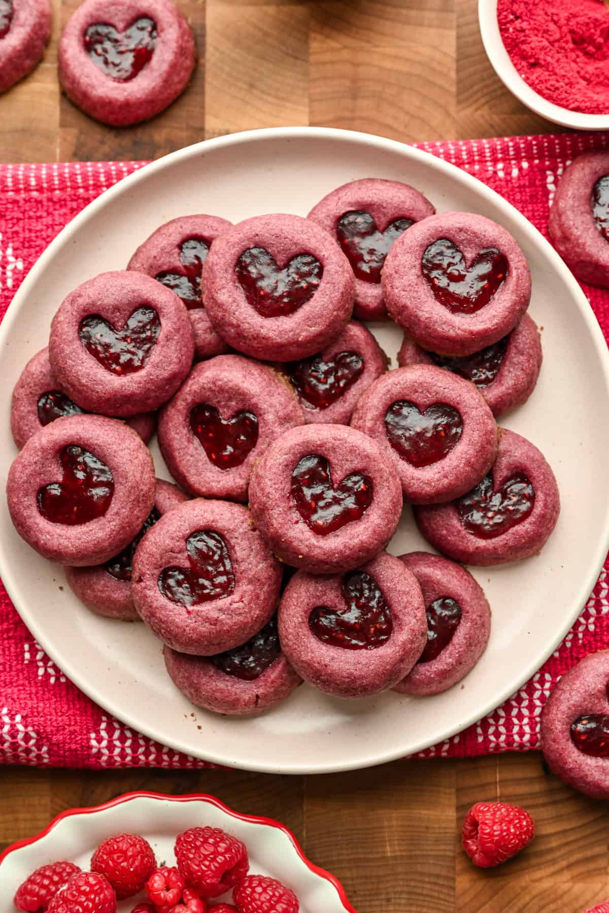 Raspberry heart tumavtryck cookies staplade upp på en tallrik.