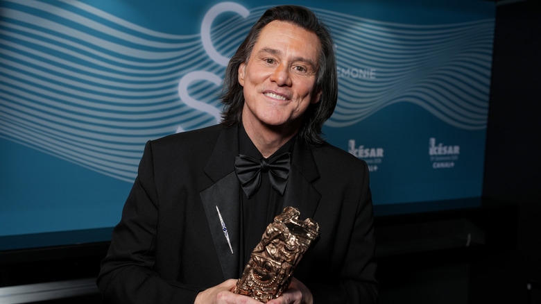 Jim Carrey håller sin Cesar Award och ler