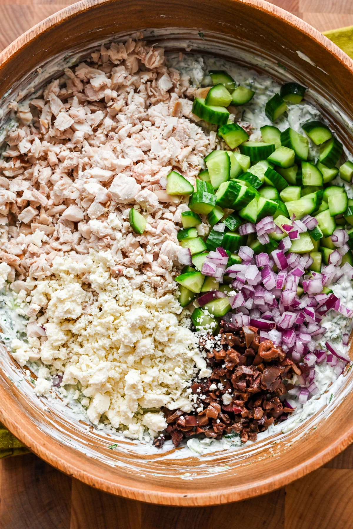 Ingredienser för tzatziki kycklingsallad läggs till skålen med dressingen.