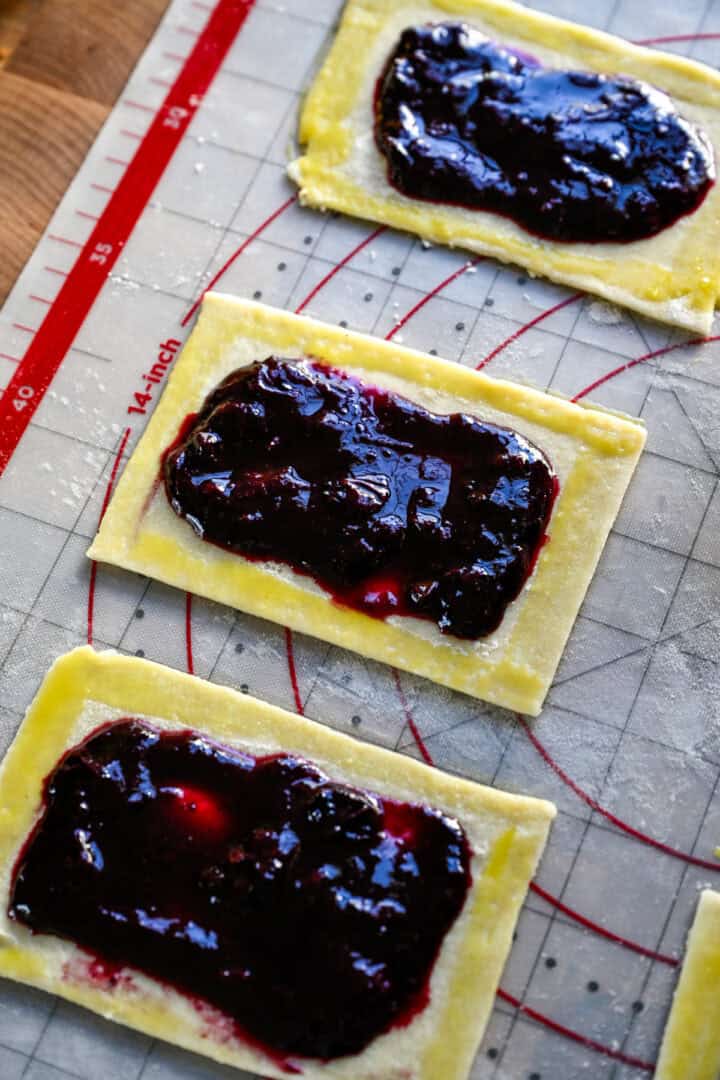 rektangel av poptärtdeg toppad med blåbärsfyllning och äggtvätt runt kanterna. 