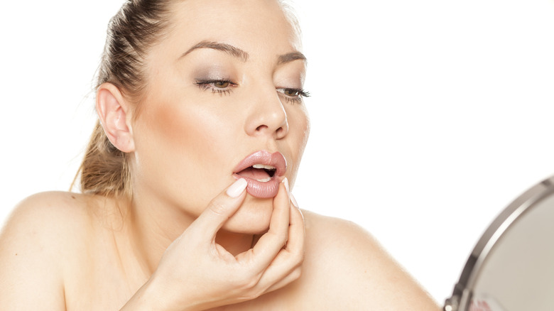 En kvinna som inspekterar sina läppar i spegeln