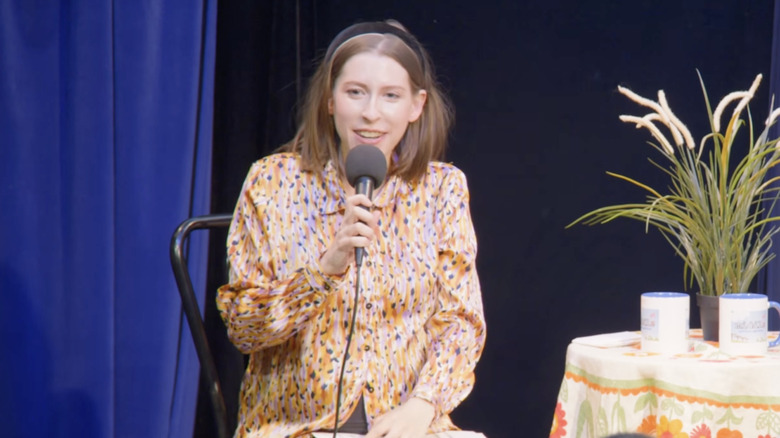 Eden Sher talar i en mikrofon när hon står på scenen för en liveshow