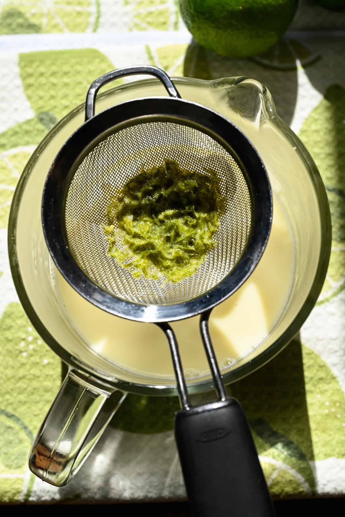 Limeskal i en liten sil över en gryta med varm grädde.
