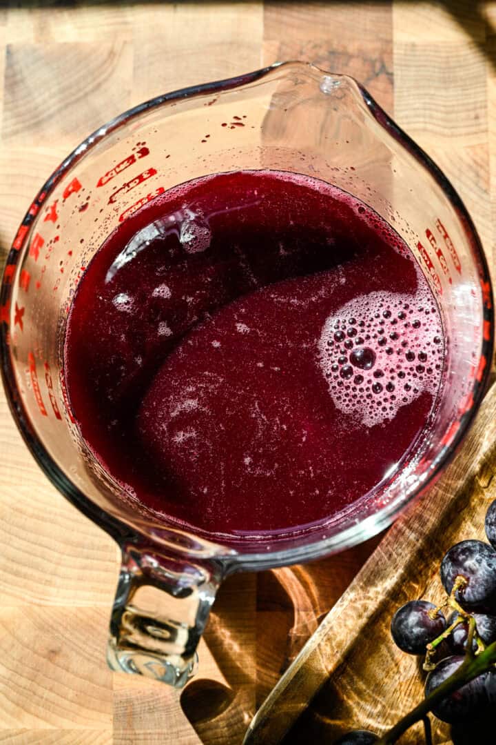 Ovanifrån av druvsodasirap i en måttkopp.