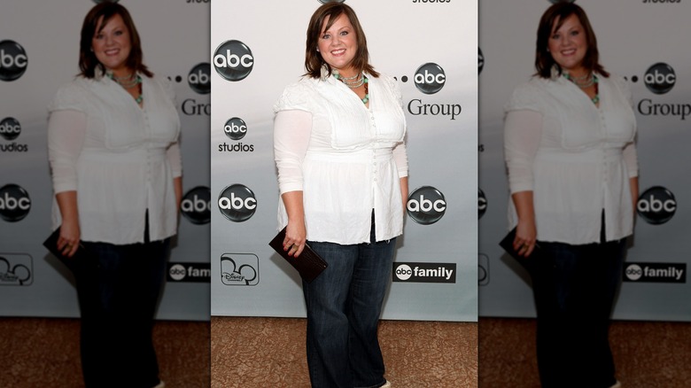 Melissa McCarthy ler i en vit topp och jeans