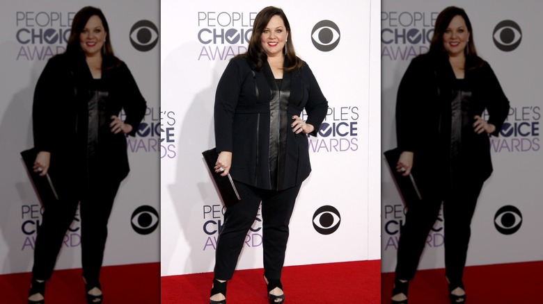 Melissa McCarthy ler medan hon bär en helsvart outfit
