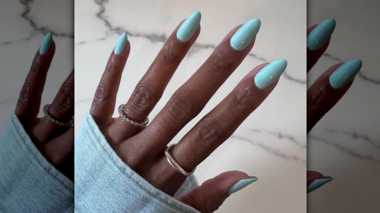 En ljusblå manikyr på en hand med ringar