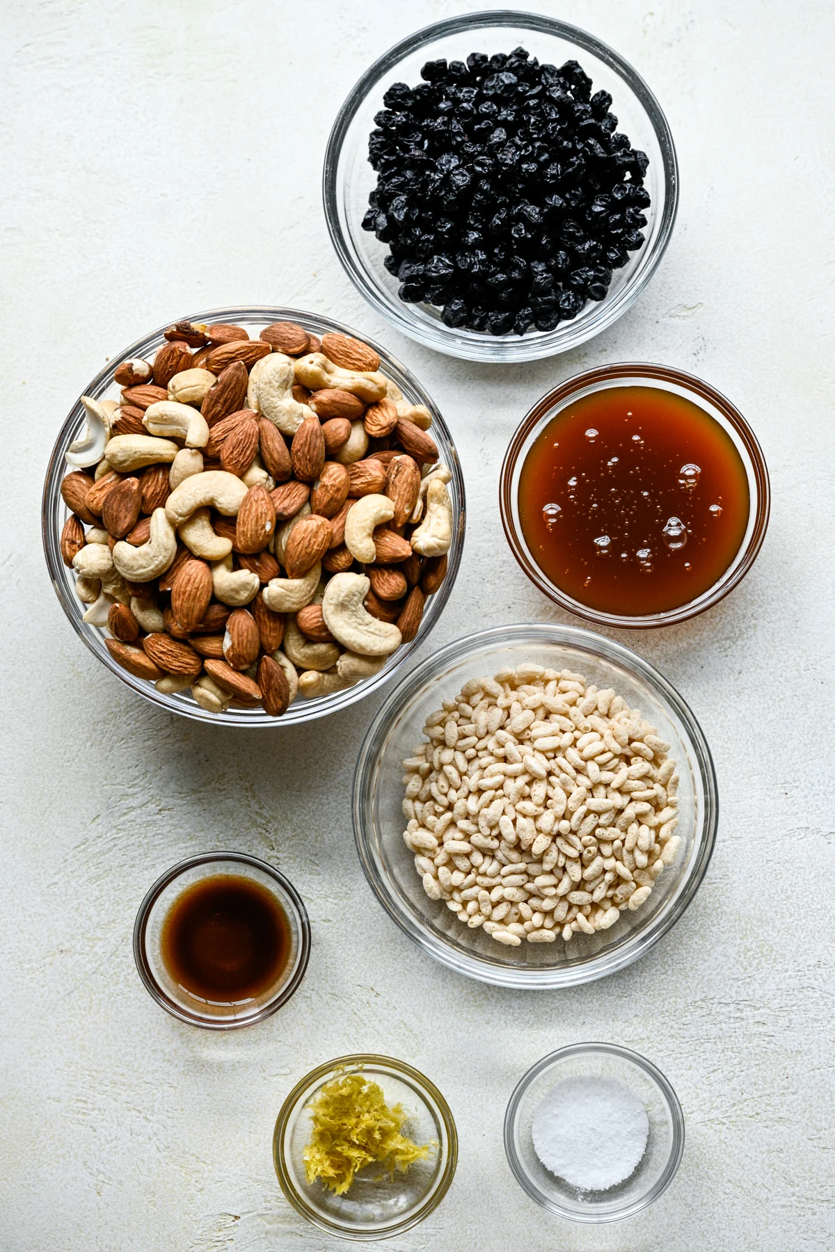 Ovanifrån av ingredienser för blåbär cashew snackbarer i små skålar.