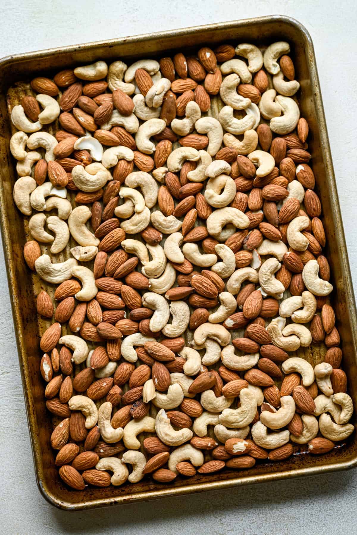 Rostade cashewnötter och mandel på en plåt.