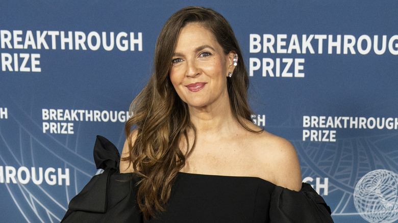 Drew Barrymore ger kameran ett mjukt leende under en fotografering på röda mattan