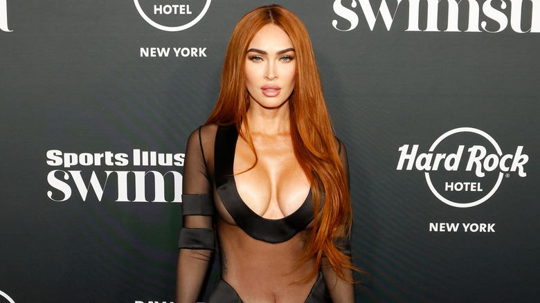 Megan Fox bär en stupande, skir svart klänning och har rött hår avskilt på mitten