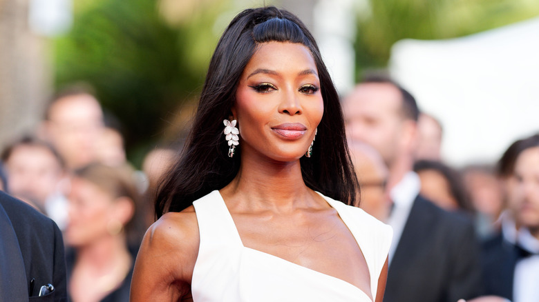 Naomi Campbell bär en vit klänning och en full glam makeup-look på ett utomhusevenemang