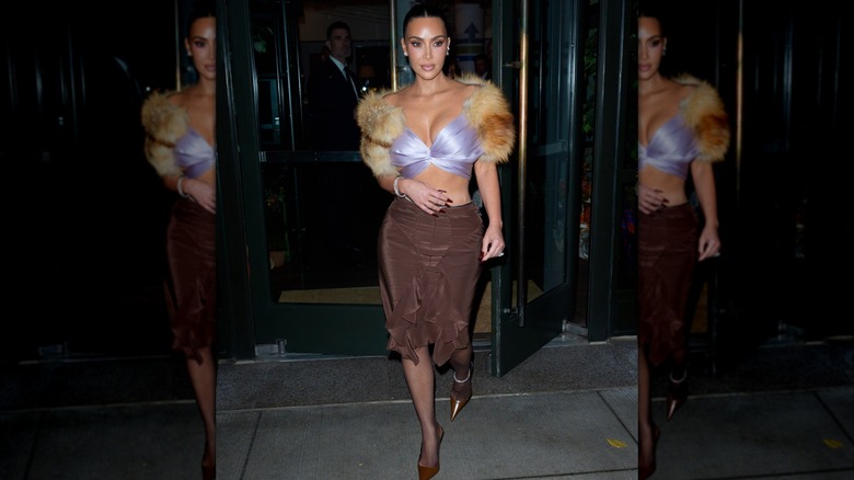 Kim Kardashian är fotograferad i en lila päls-trimmad topp och brun kjol i New York City 2025.