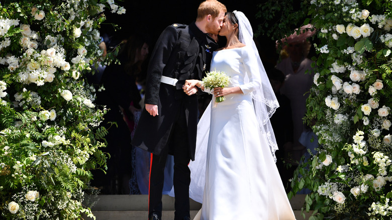 Meghan Markle i sin bröllopsklänning och prins Harry delar en kyss på sin bröllopsdag