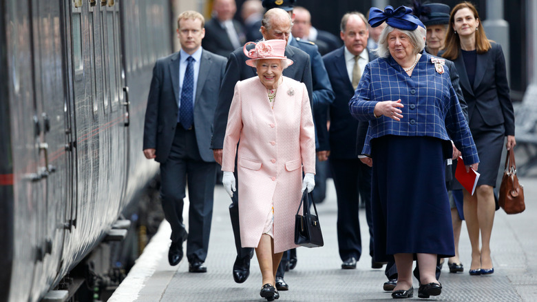 Drottning Elizabeth sticker ut i ljusrosa bland en skara människor