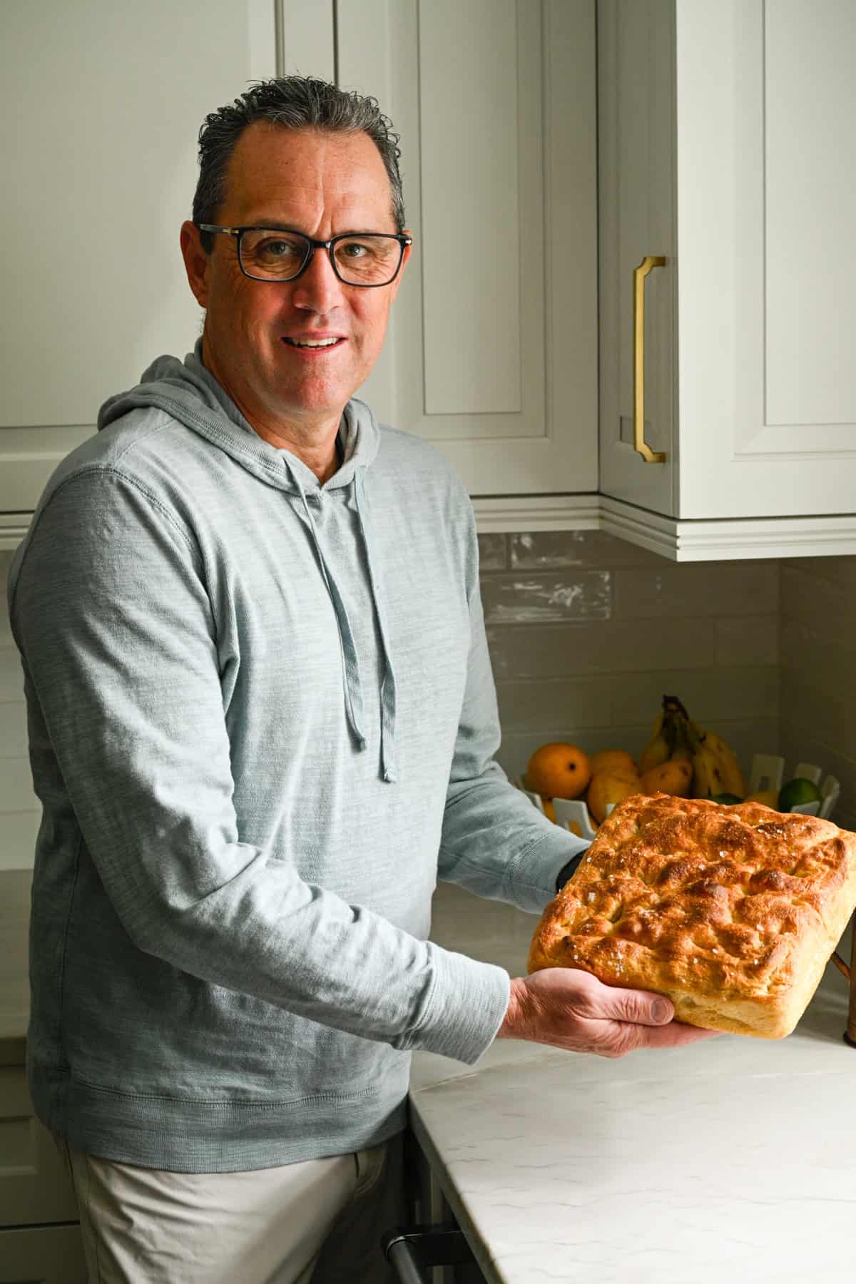 Min pappa i köket håller i en limpa hemmagjord focaccia. 
