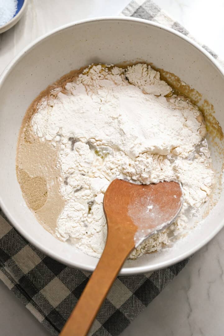 Vatten, jäst, olivolja och mjöl i en mixerskål innan du blandar ihop. 