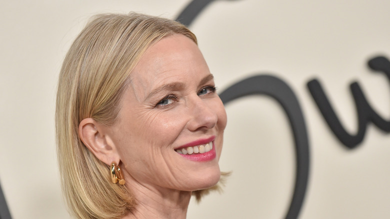 Naomi Watts ler mot kamerorna under ett reklamevenemang