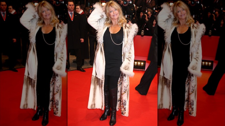 Goldie Hawn på ett event på röda mattan klädd i en helsvart outfit och en lång silkeslen kappa med pälskant.