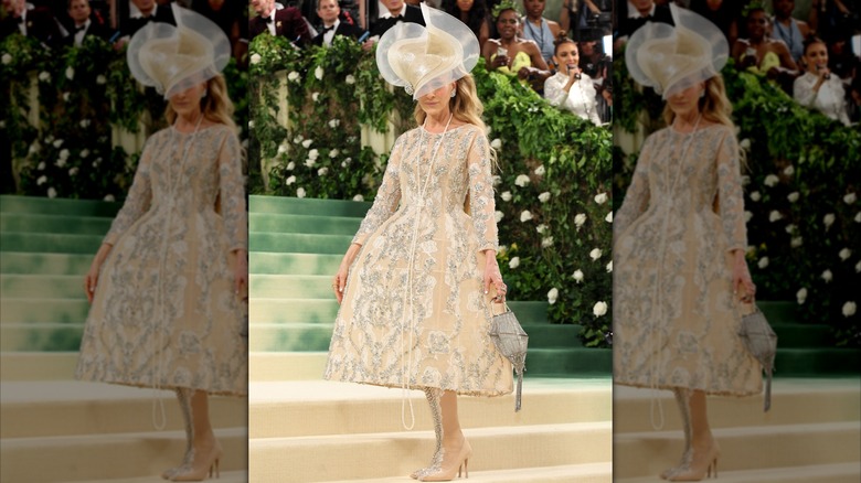 Sarah Jessica Parker poserar på Met Gala 2024 i en invecklad guldklänning med en stor hatt.