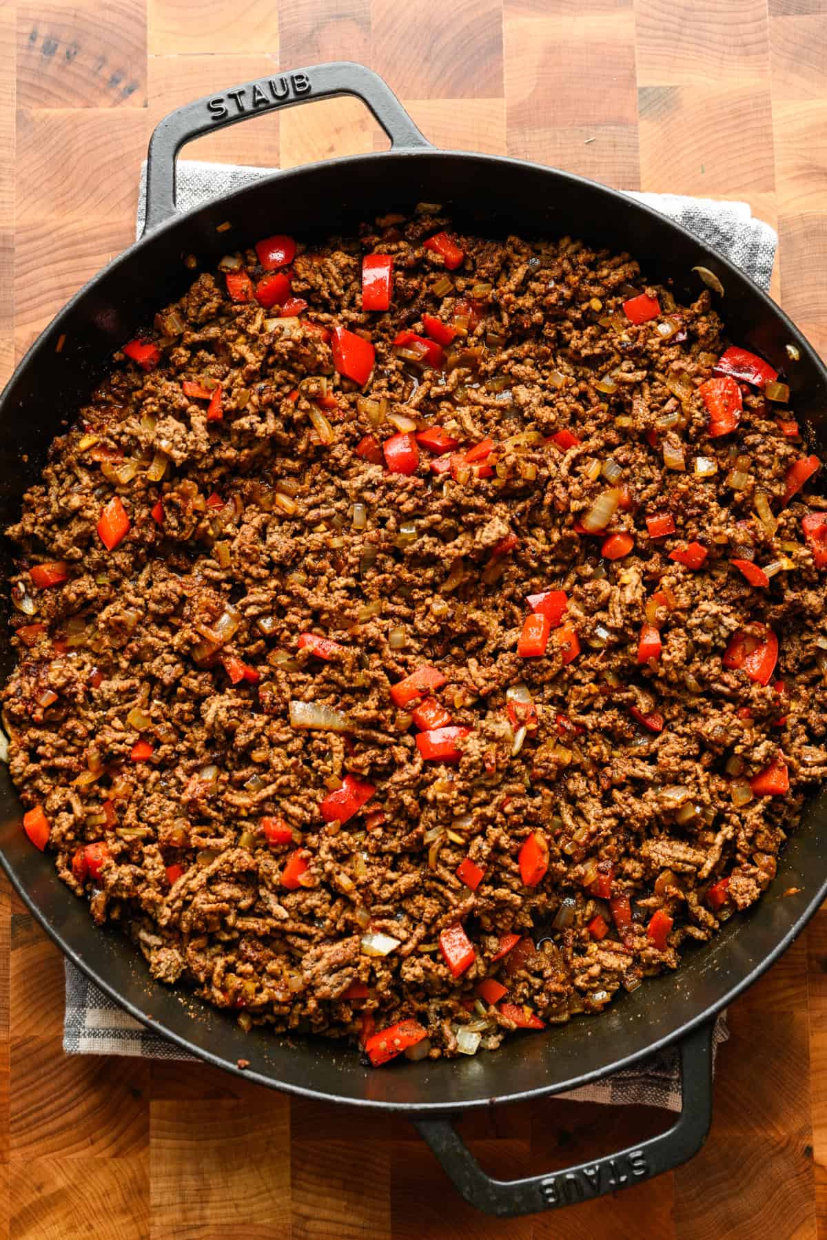 Lök och röd paprika tillsätts i stekpannan med nötköttet.