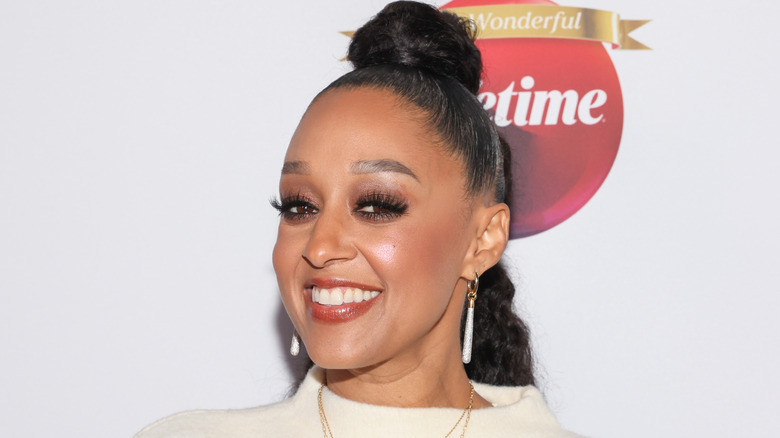 Tia Mowry 2025 ler under ett evenemang på röda mattan