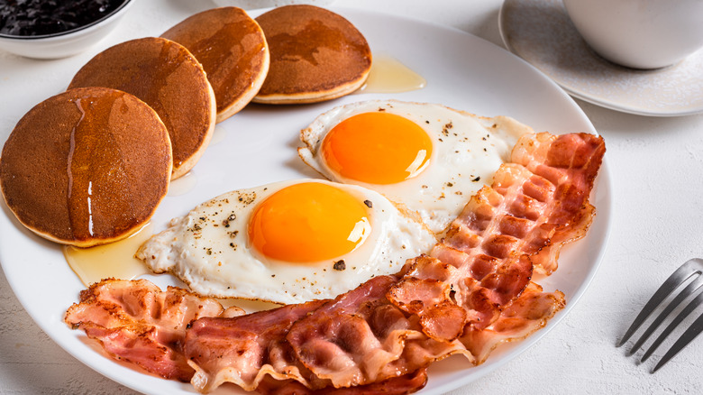 En tallrik med bacon, ägg och pannkakor