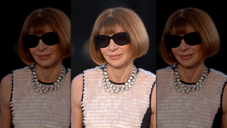 Anna Wintour ler iförd svarta solglasögon och ett kristallhalsband