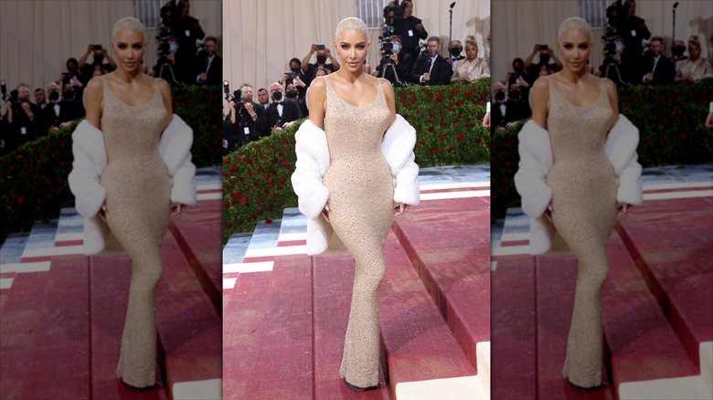Kim Kardashian poserar i en naken klänning och en vit päls