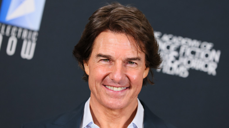 Tom Cruise ler och poserar på ett evenemang