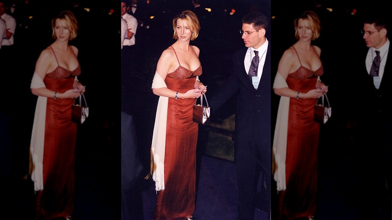 Lisa Kudrow poserar på en röd mattan-event i en röd klänning med en vit halsduk och kort hår.