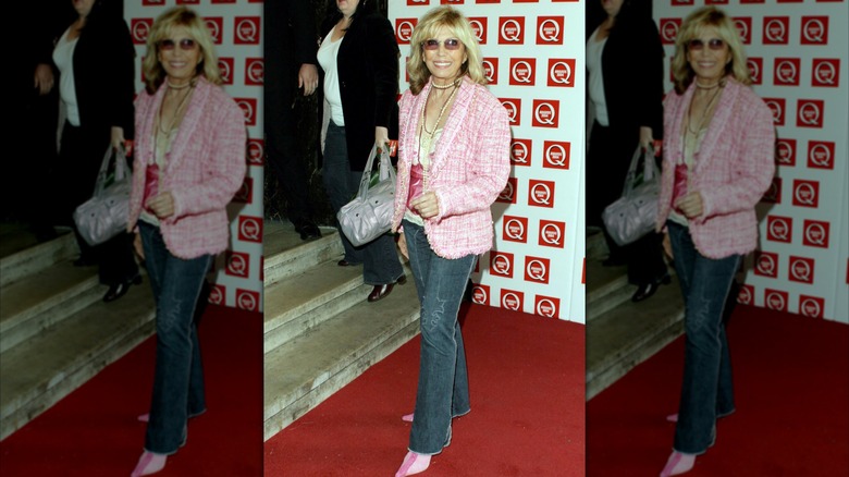 Nancy Sinatra poserar på en röd matta iklädd mörka jeans med en rosa kavaj och rosa skor.