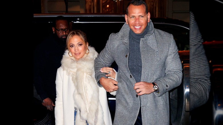 Jennifer Lopez i en vit päls som håller fast i Alex Rodriguez klädd i en grå peacoat.