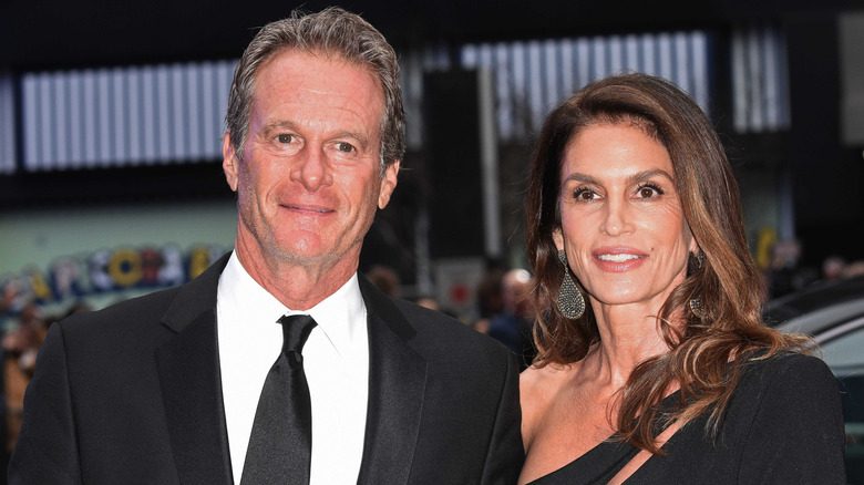 Rande Gerber i svart kostym bredvid och Cindy Crawford i svart klänning poserar utanför.