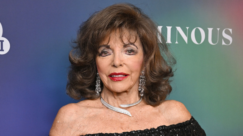 Joan Collins poserar i en svart klänning