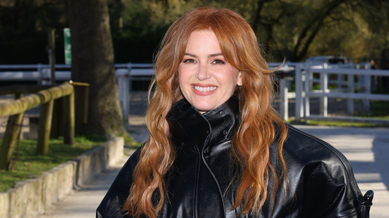 Isla Fisher ler utanför iförd en svart skinnjacka med håret neråt.