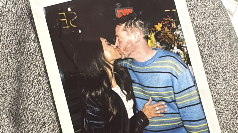 Ett foto på en polaroid med Brenda Song i en skinnjacka som kysser Macaulay Culkin i en randig tröja.