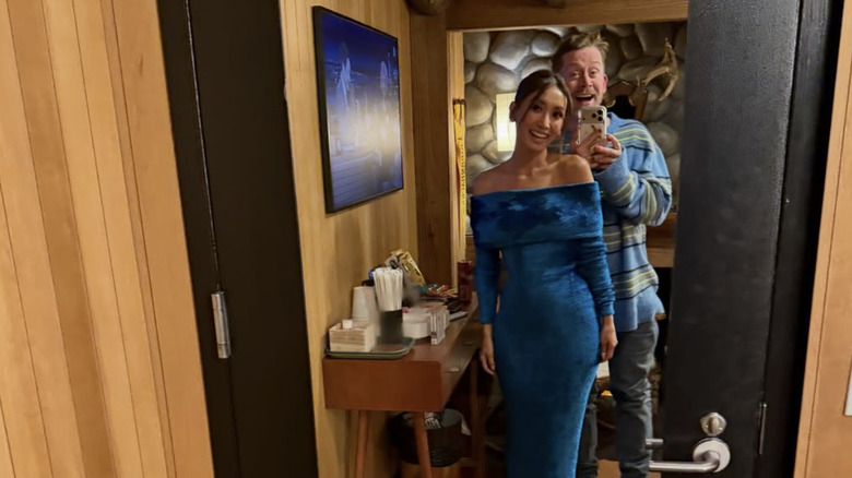 Brenda Song i en blå mockaklänning medan Macaulay Culkin står bakom henne i en mysig tröja och jeans.