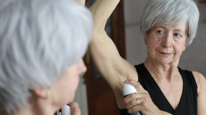 Senior kvinna som applicerar deodorant i badrummet